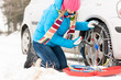 © CandyBox Images - Woman putting chains on car winter tires