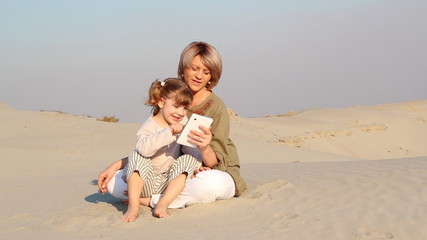 Wall Mural - mother and daughter play with tablet in desert