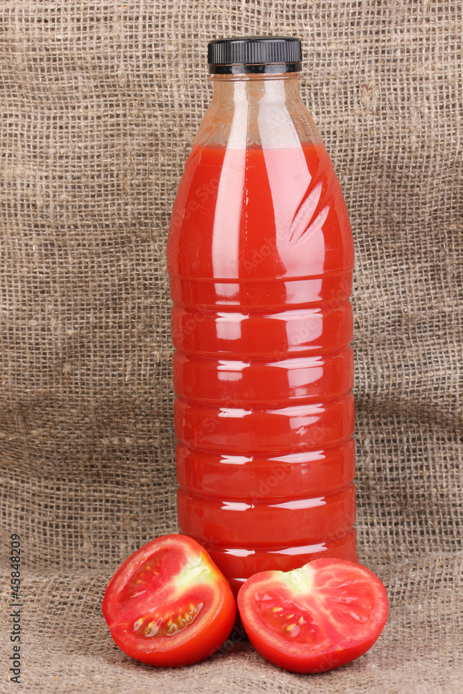 Tomato juice in bottle on sackcloth background