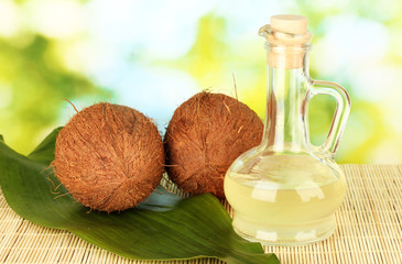 Wall Mural - decanter with coconut oil and coconuts on green background