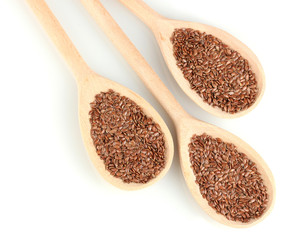 Wall Mural - flax seeds in wooden spoons on white background close-up