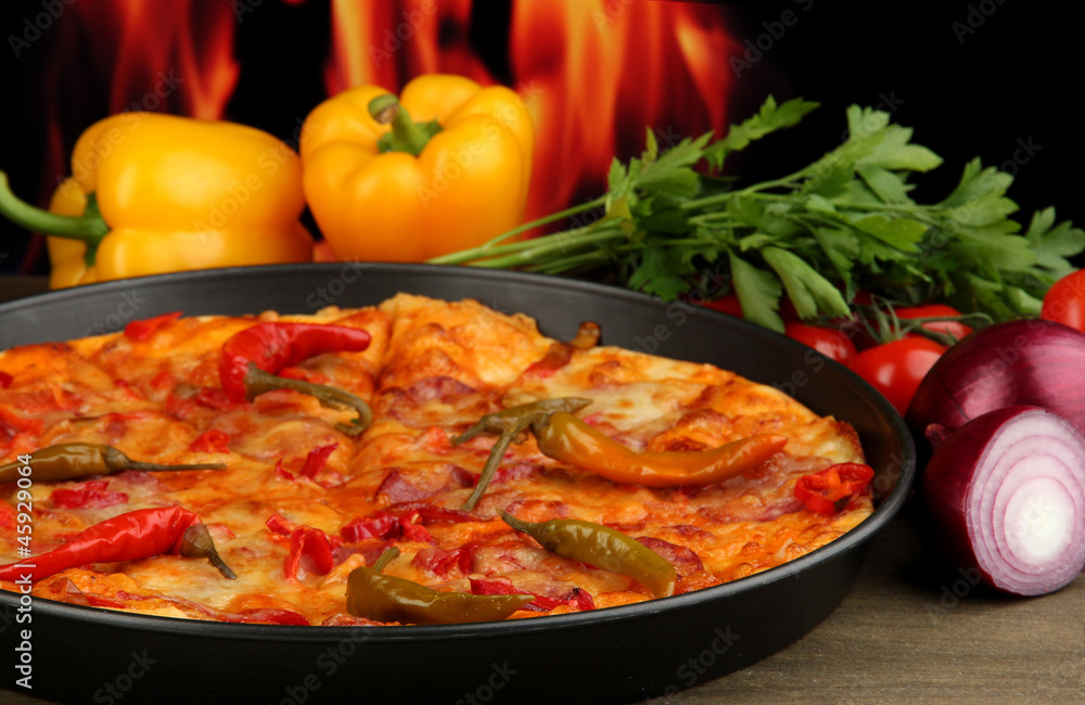 Tasty pepperoni pizza in pan with vegetables on flame