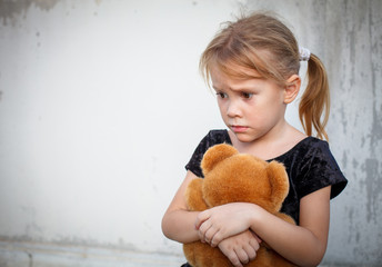 sad little girl on background the wall