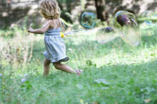 Young Cute Child Girl Blowing Big Soap Bubbles