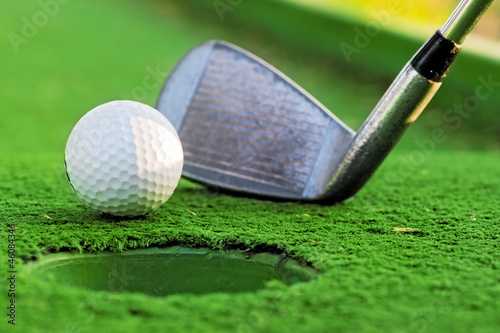 Board z aluminiowym obramowaniem Piłeczka golfowa w pobliżu otworu na zielonym boisku.