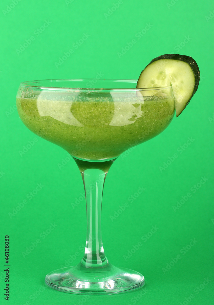 Green vegetable juice in coctail glass on green background