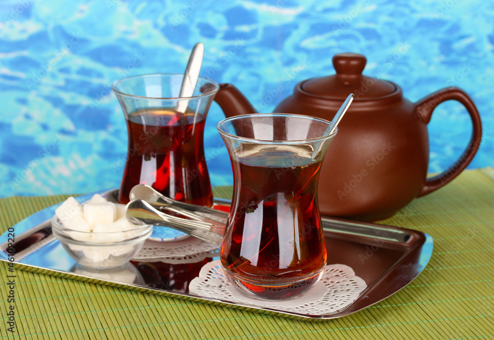 glass of Turkish tea and kettle on color background