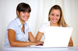 © pablocalvog - Smiling young businesswomen using laptop together