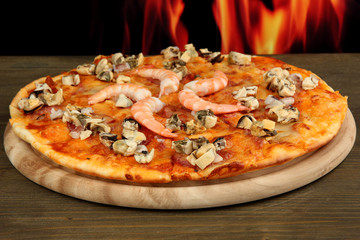 Poster - Delicious pizza with seafood on stand on flame background