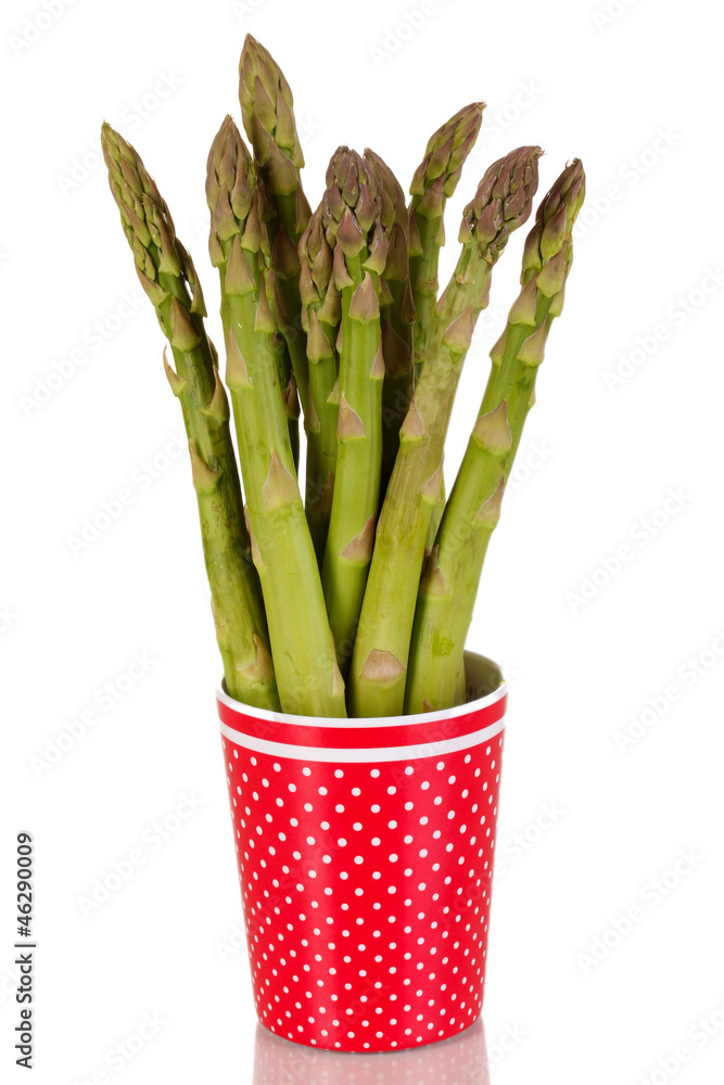 Fresh asparagus in colorful pot isolated on white.