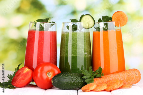 Fototapeta na wymiar Fresh vegetable juices on wooden table, on green background