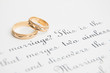 Two wedding golden rings on a paper with text of wedding vow