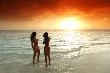 Two women enjoying sunset on beach