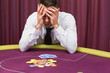 Man holding head in hands at poker table