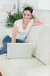 © WavebreakMediaMicro - Woman sitting on the couch and smiling while using a laptop