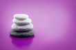 Assorted balanced stones (feng shui) on purple with copy space