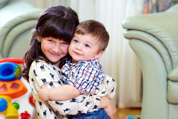 Fototapete - beautiful little brother and sister embracing in home interior