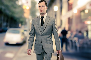 Wall Mural - Man in classic grey suit with briefcase walking outdoors