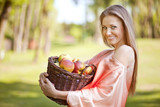 Uśmiechnięta kobieta z koszem jabłek