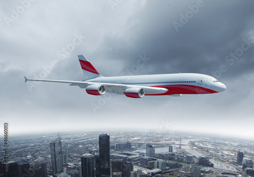 Obraz w ramie White passenger plane flying above a city