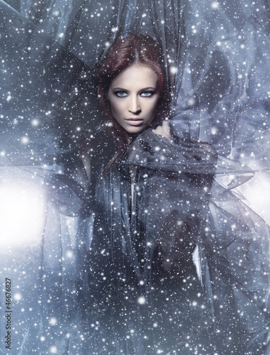 Fototapeta na wymiar A young redhead woman posing on a snowy blue silk background