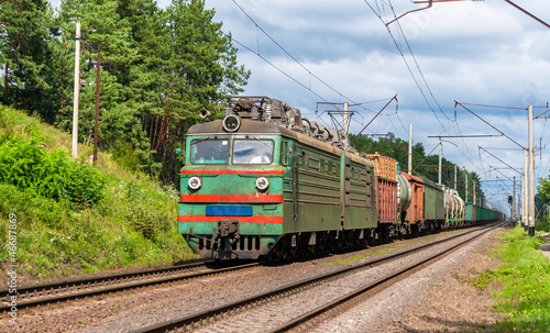 Board z aluminiowym obramowaniem Pociąg towarowy ciągnięty przez starą lokomotywę elektryczną. 