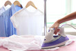 © Africa Studio - Woman hand ironing a shirt, on cloth background