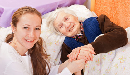 Young doctor holds the elderly woman hands