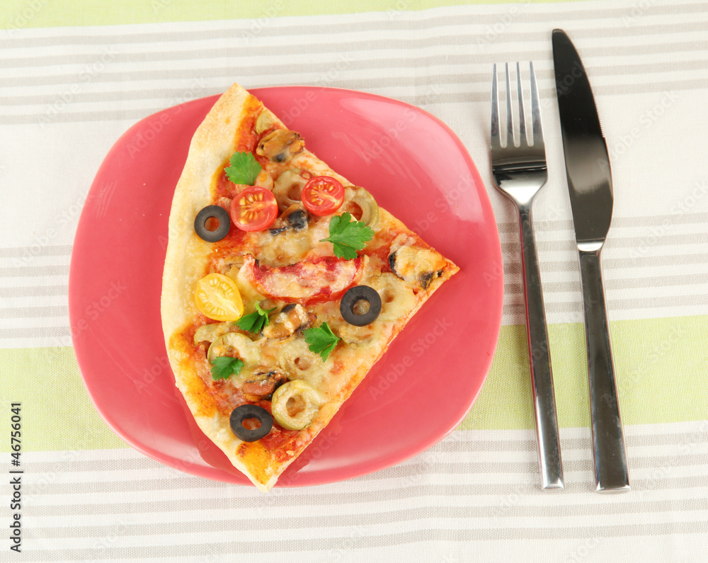 plate with a slice of delicious pizza on tablecloth close-up