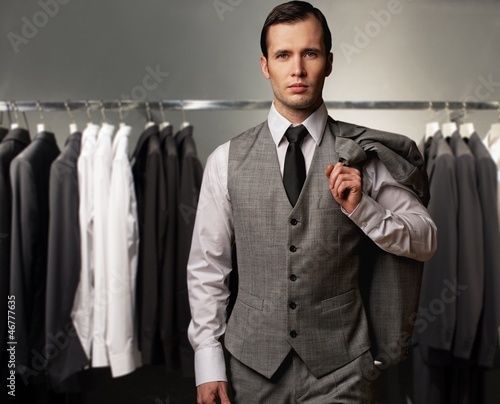biznesmen-w-klasycznej-kamizelce-przeciw-rzedowi-kostiumy-w-sklepie