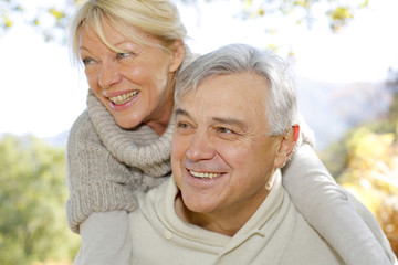 Wall Mural - Senior man giving piggyback ride to wife