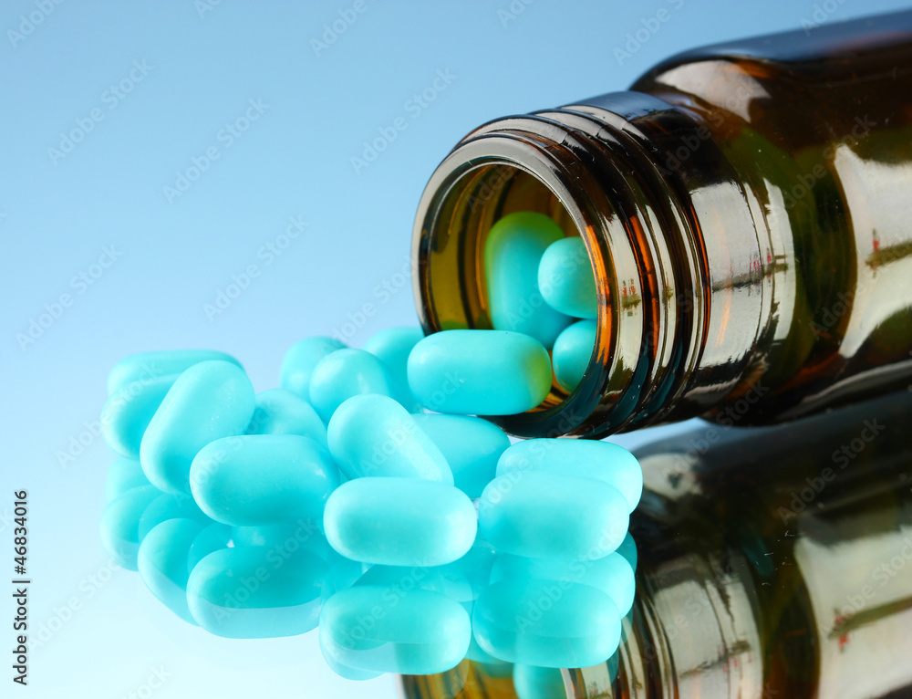 pills in bottle, on blue background