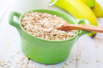 Wall Mural - Oat flakes in the green bowl with banana and milk