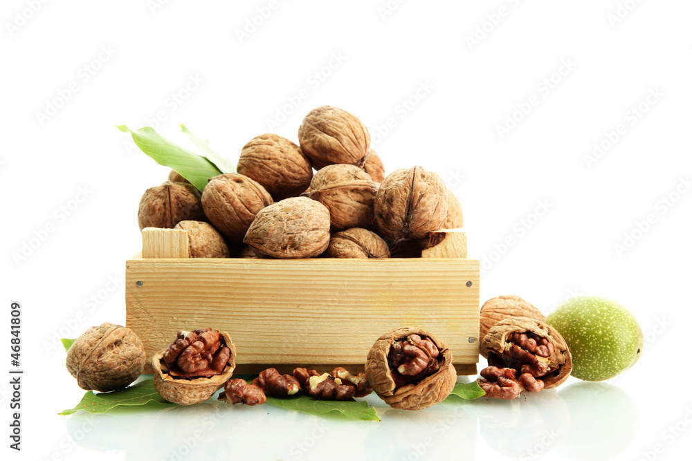 walnuts with green leaves in woooden crate, isolated on white
