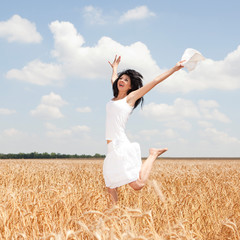 Happy woman jumping in golden wheat