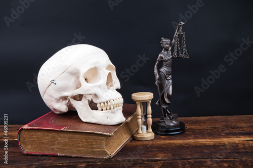 Fototapeta na wymiar old book human scull and temida statue