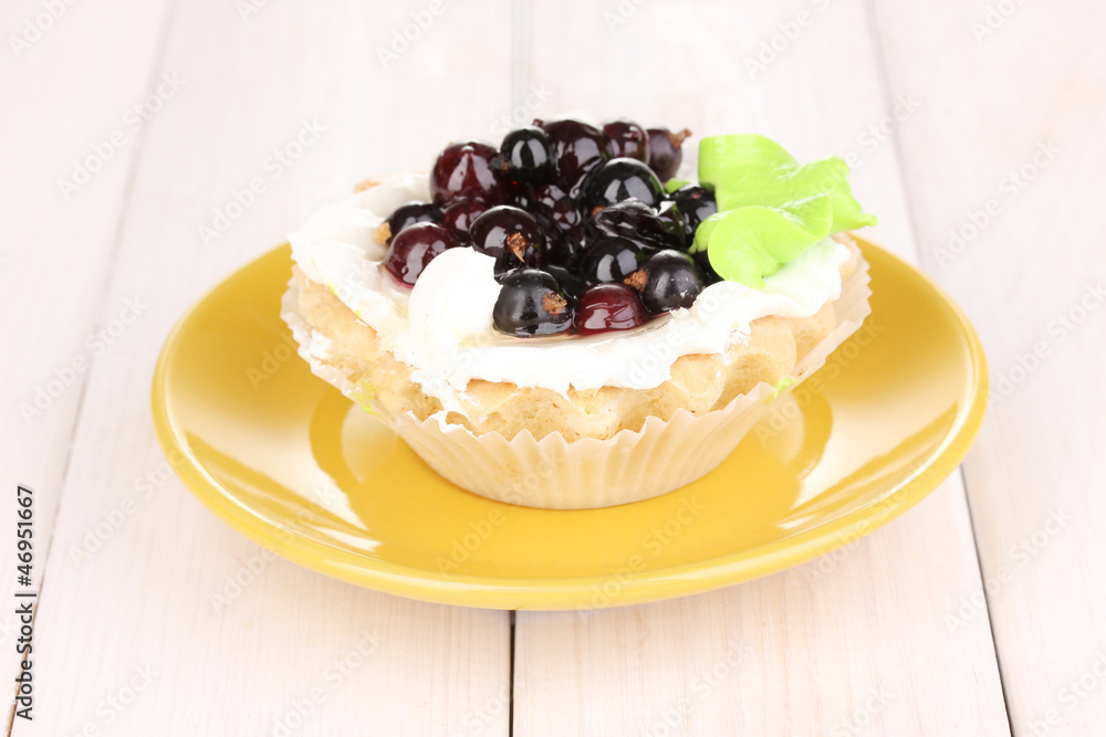 sweet cake with berries on saucer on wooden background