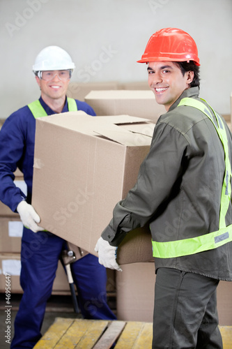 Fotografie, Obraz Foremen Lifting Cardboard Box in Warehouse