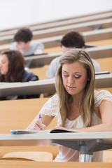 woman sitting in lecture while writing notes