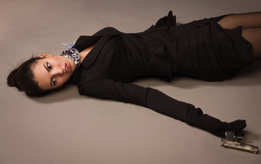 Wall Mural - Woman in a black suit with gun lying on the floor