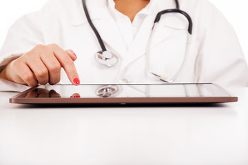 Female doctor with tablet computer at the desk, isolated over wh