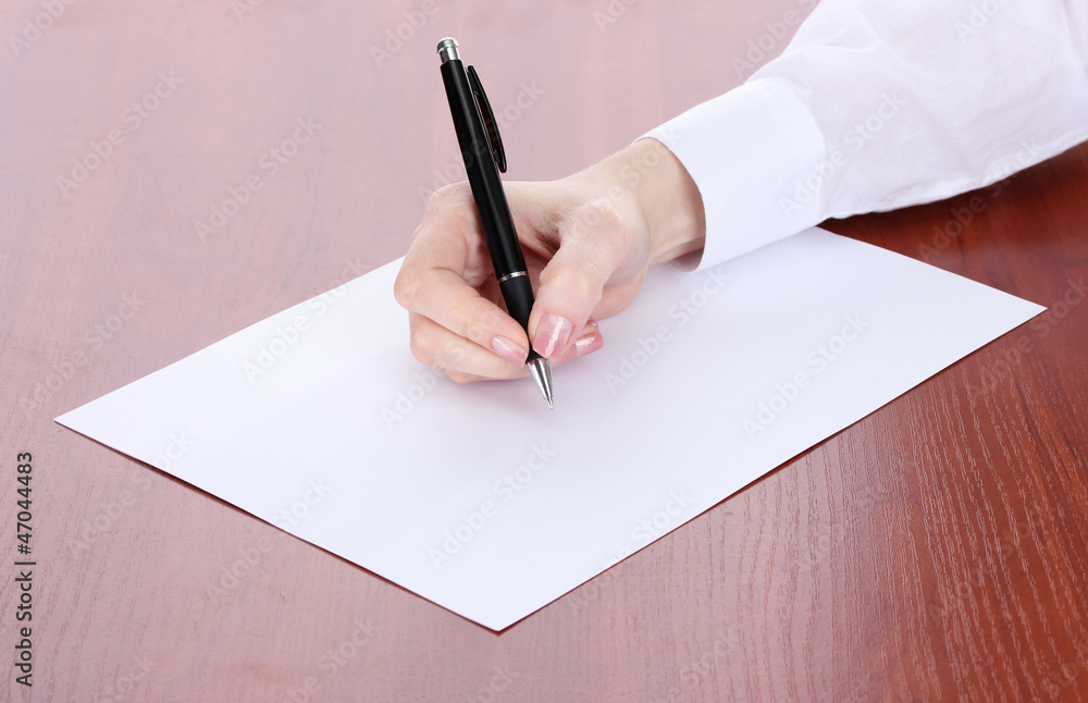 woman hand writing on paper, on wooden table.