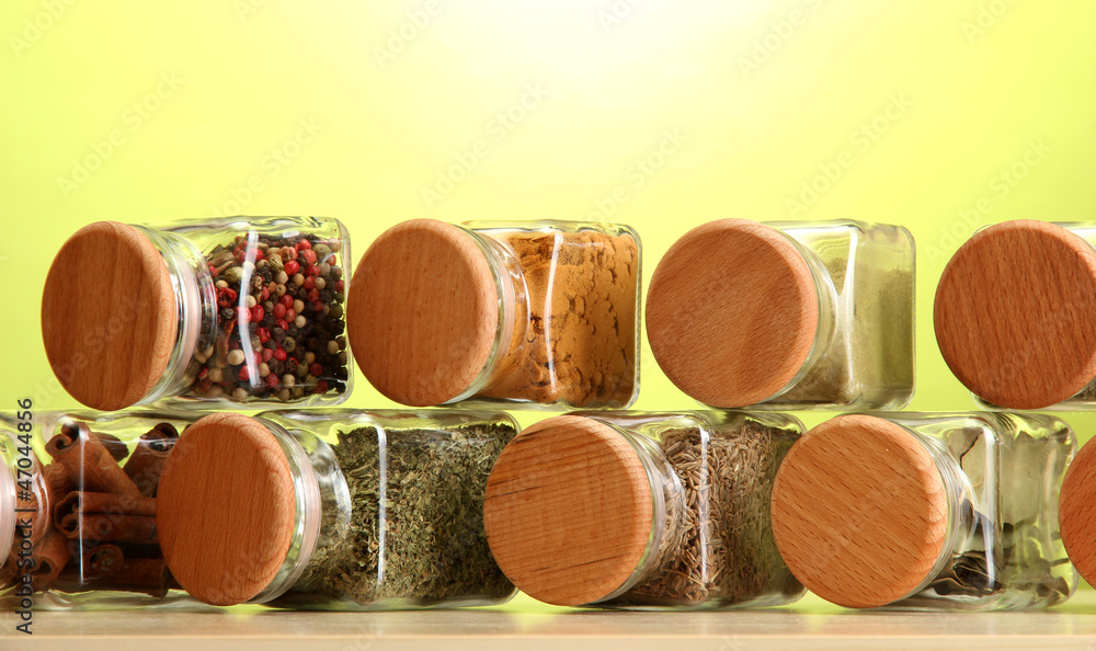 powder spices in glass jars on green background