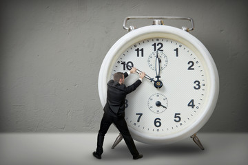 Wall Mural - Businessman pulling a clock hand backwards