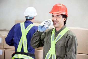 Wall Mural - Foreman Drinking Coffee While Colleague Working At Warehouse