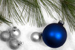 Silver and blue ornaments in the snow with pine branch