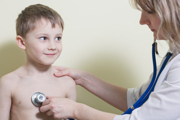 Young and cute female doctor visiting with a stethoscope a littl