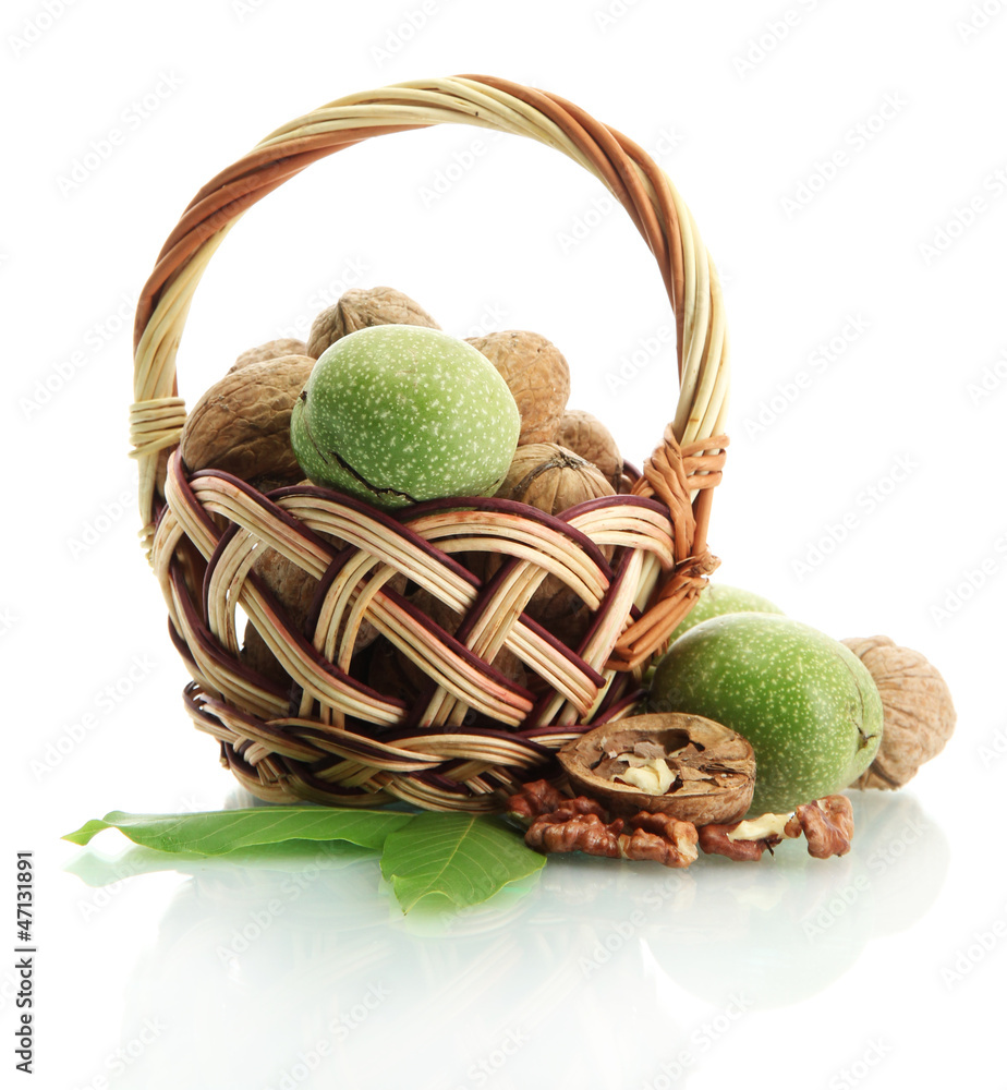walnuts with green leaves in basket, isolated on white