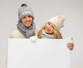 couple in a winter clothes holding blank board