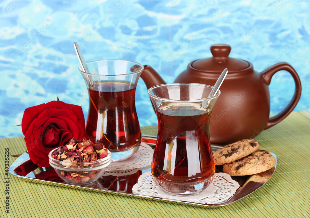 glass of Turkish tea and kettle on color background